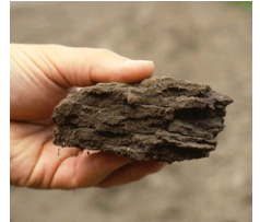 A photo of a hand holding a clump of compacted soil