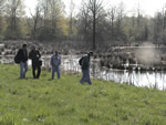group of people walking along wetland pond edge