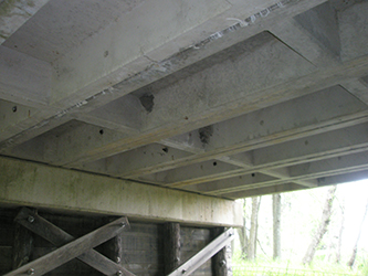 Photograph of the underside of a bridge, showing pre-stressed concrete channel beam