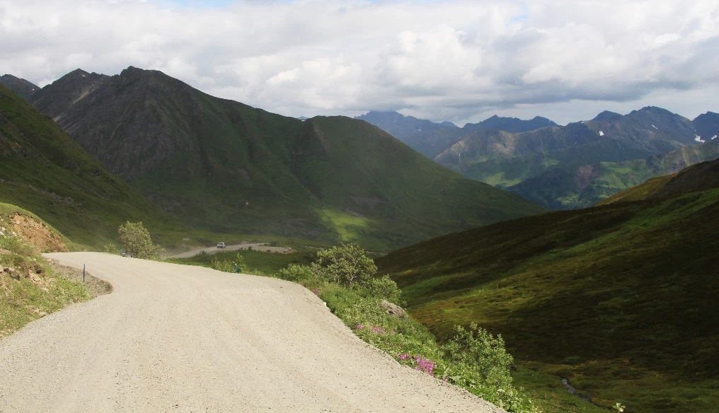 A photograph of a gravel road winding through a mountainous area.