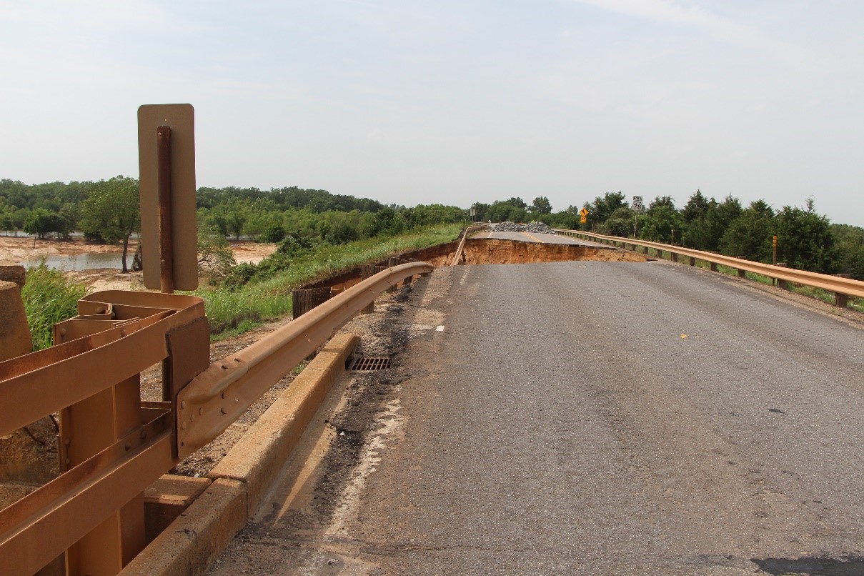 A roadway showing a washed out and destroyed portion of the road.