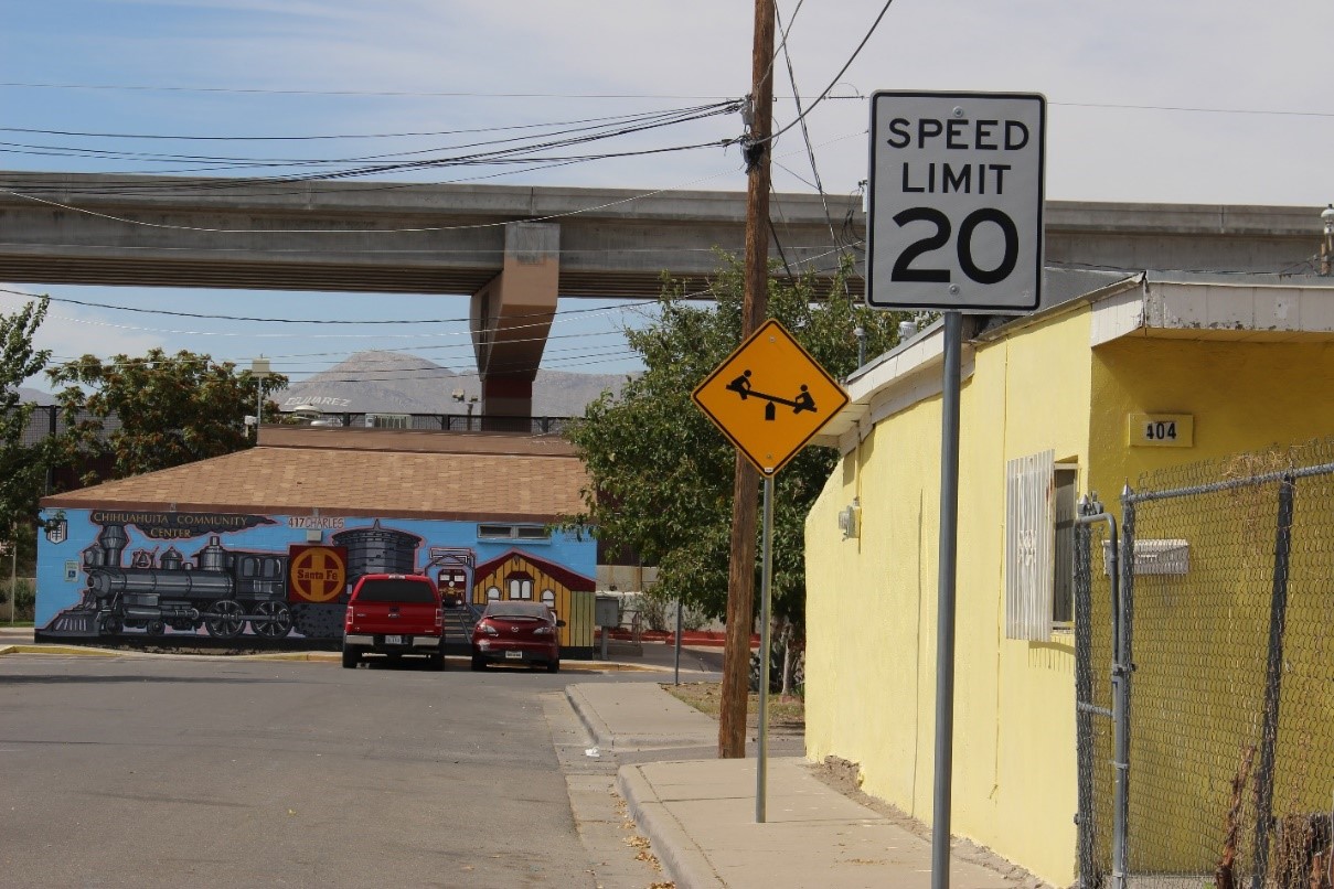 A photograph of a street corner with a couple of buildings and a highway running through the area.