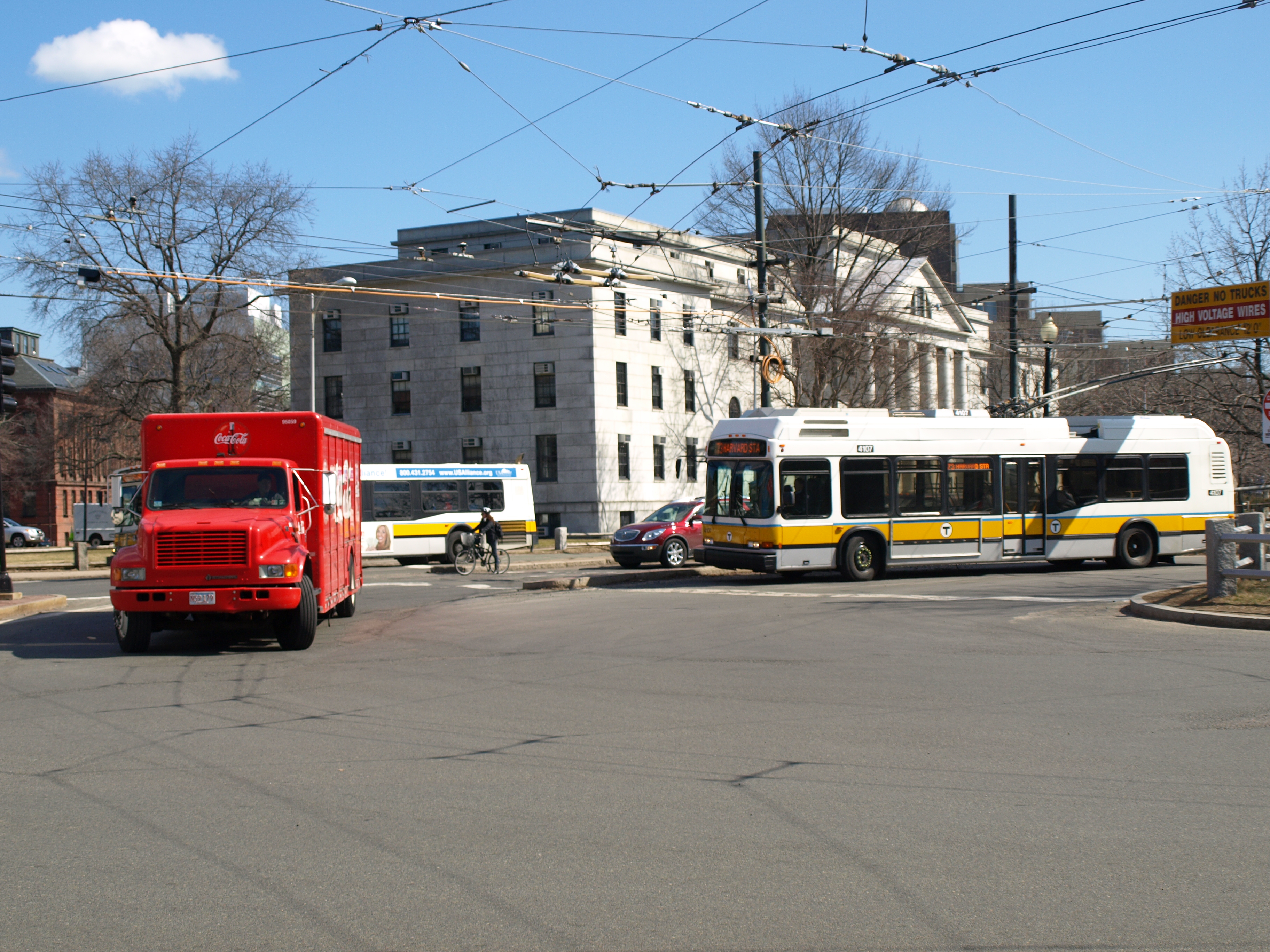 A street with a red truck and two buses entering a roundabout