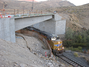 Photograph of a train passing underneath a bridge during the bridge's construction