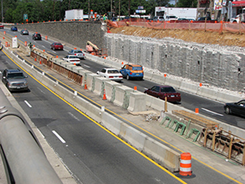 Photograph of cars traveling on opposite lanes of a service road under construction