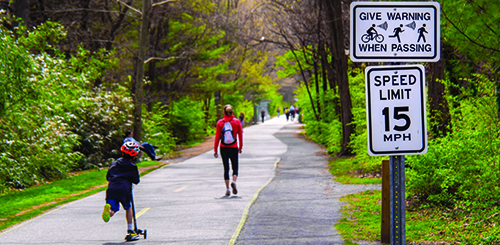 a pedestrian and a child using an e-scooter on a bike and walking path in urban Washington, D.C.