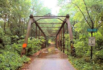 Color photograph of a historic bridge in a lushly wooded area