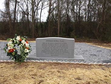 Photograph of the relocated burial place with a large headstone describing the burial place.