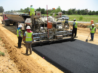 photograph of a road construction crew laying a new road with warm-mix asphalt pavement