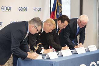 photo of four men leaning over a table signing the Section 106 PA documents