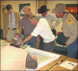 Pictured are a group of men, reviewing project plans during this public hearing.