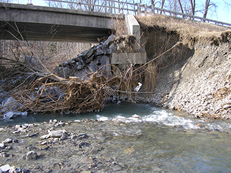 Photograph underneath the State Route 34 bridge over Cayuga Inlet showing significant riverbank erosion