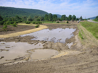Photograph of a section of a large rural field that has been plowed as a beginning stage of wetland creation