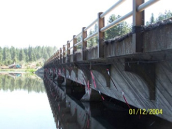 Photograph of a bridge with colorful streamers hanging along the underside edge to discourage migratory birds from building nests