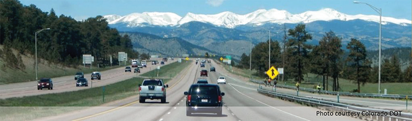 photo, courtesy of Colorada DOT, of moderate traffic on a rural highway with a snow-covered mountain range in the background