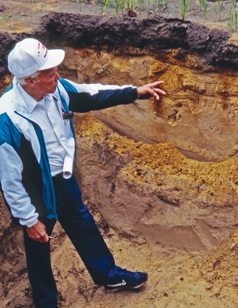 Photo of man pointing to layer of topsoil