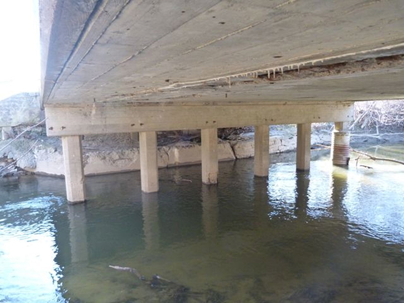 Photograph of the underside of a bridge, showing a continuous concrete slab supported by pillars