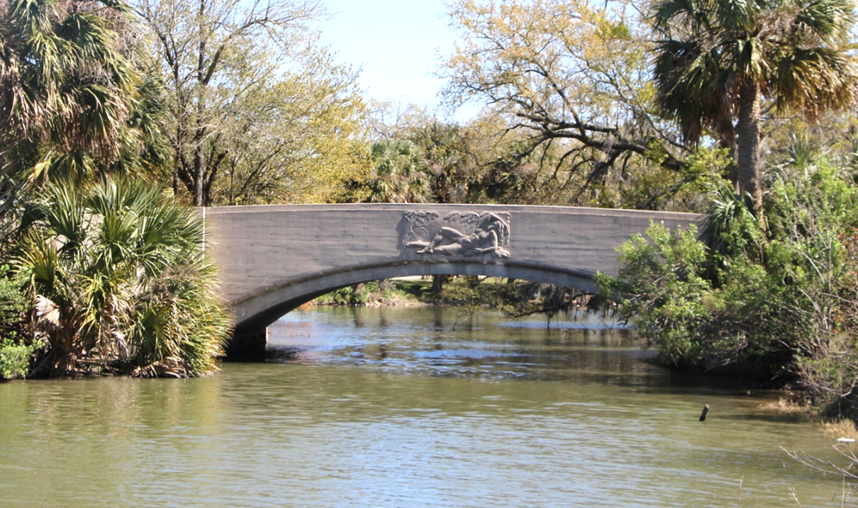 A photograph of a reinforced-concrete arch bridge spanning a waterway located in City Park in New Orleans.