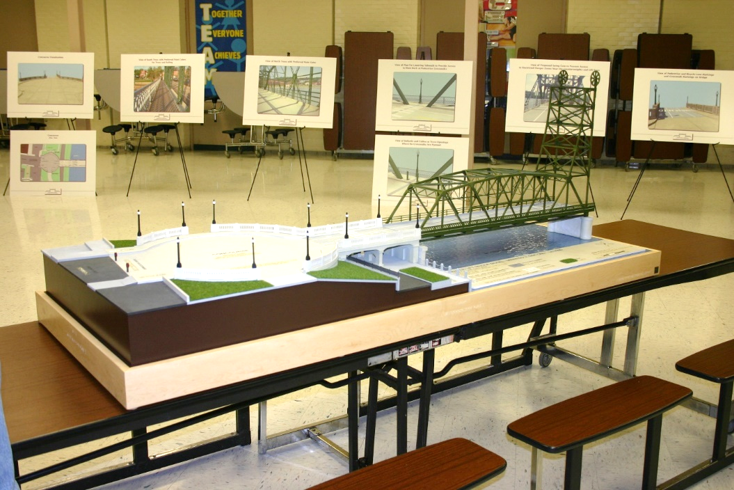 A table with a diarama of a bridge, walkway, and river bank. In the background there are posterboard displays with images of bridges on them.