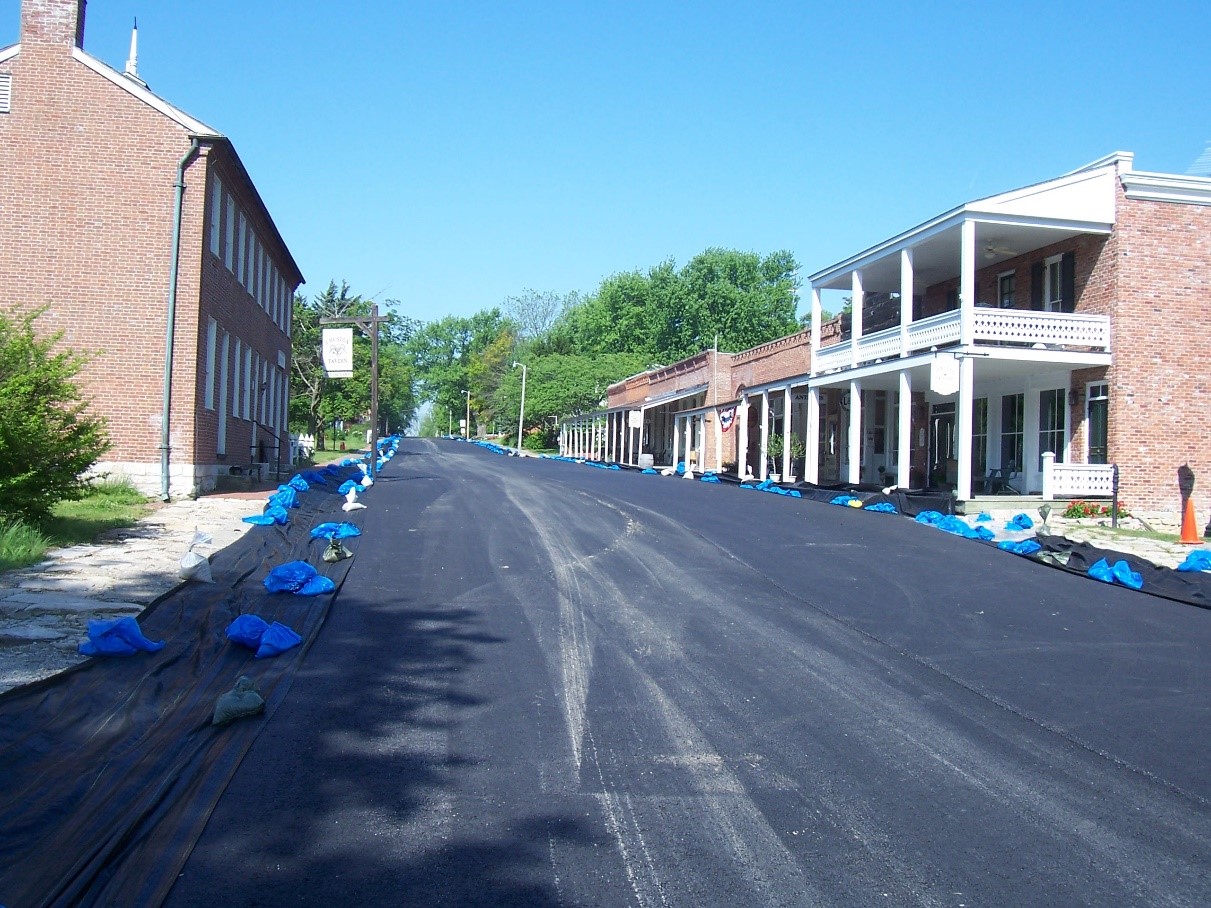 A streetview lined with brick buildings with blue bags in front of the buildings.
