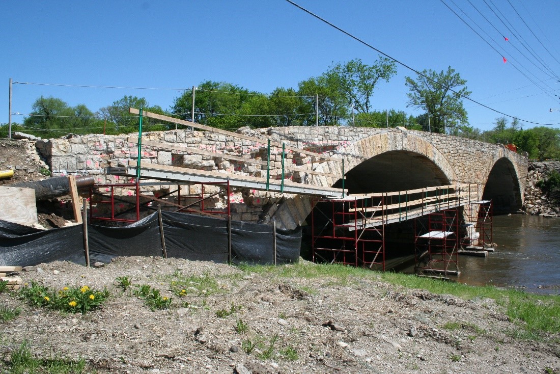 A photograph of a double arched stone bridge with scaffolding surrounding the bridge.