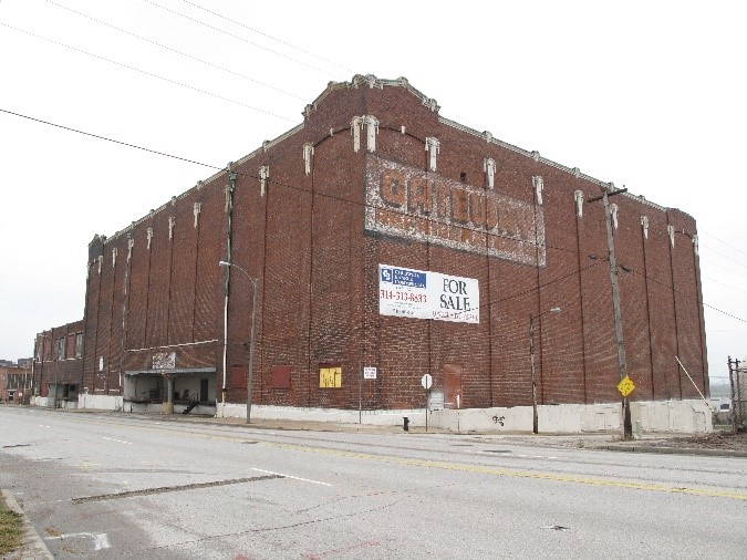 A photograph of a dilapidated historic brick building on a street corner.