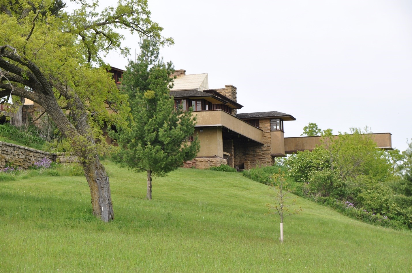 A photograph of a house from a distance on a grassy hilltop.