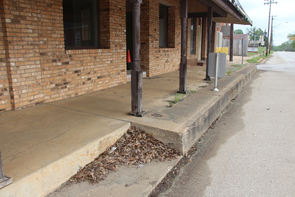 A photograph of a covered walkway next to a historic building with steep curbs.