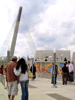 Photograph of the pedestrian bridge and a community art mural on one bridge wall section