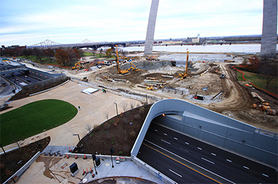 aerial photo looking from above the completed freeway cap towards the Arch park grounds construction below the Gateway Arch