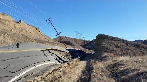 photo of a road and utility poles damaged from a landslide 