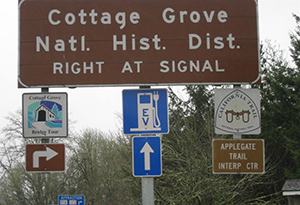 Photograph of Cottage Grove National Historical District signage, which includes an EV charging station sign